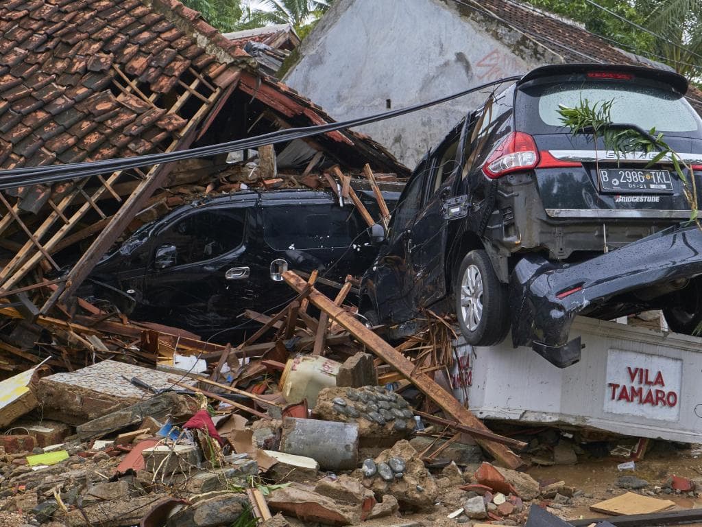 Wrecked cars lie on top of the ruins of a house destroyed by the tsunami. Picture: Getty